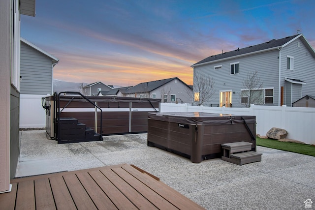 wooden deck featuring a hot tub, a fenced backyard, and a patio area