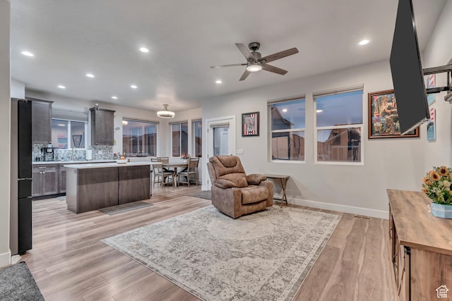 living room with a ceiling fan, recessed lighting, baseboards, and light wood-type flooring