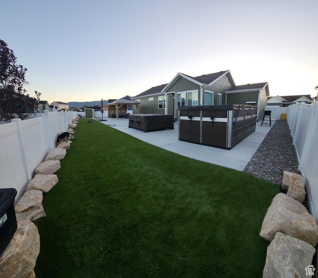view of yard featuring a hot tub, a fenced backyard, and a gazebo