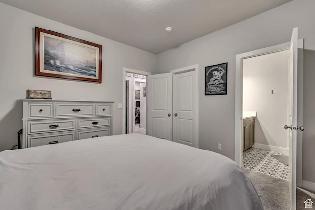bedroom featuring baseboards, ensuite bath, and carpet