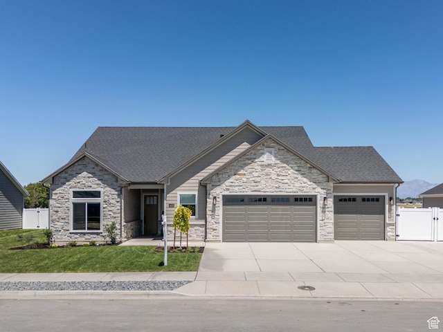 view of front of house featuring fence, a gate, a front lawn, a garage, and a shingled roof