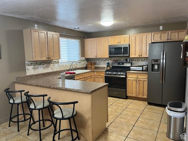 1213 N Winston Dr, Kaysville, UT 84037 - kitchen featuring appliances with stainless steel finishes, a peninsula, light brown cabinets, decorative backsplash, and a textured ceiling