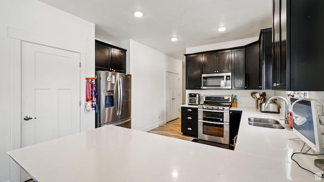 7756 W Bellfield Rd, Magna, UT 84044 - kitchen with light countertops, light wood-style flooring, recessed lighting, appliances with stainless steel finishes, and a sink