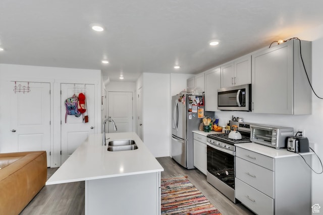 kitchen with a sink, light countertops, light wood-style floors, and appliances with stainless steel finishes