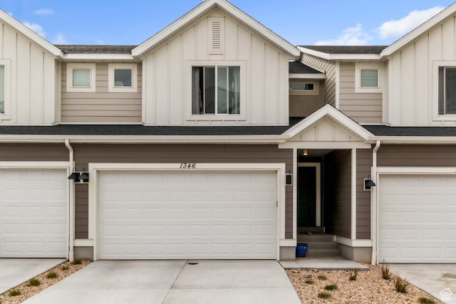 townhome / multi-family property featuring an attached garage, board and batten siding, and roof with shingles