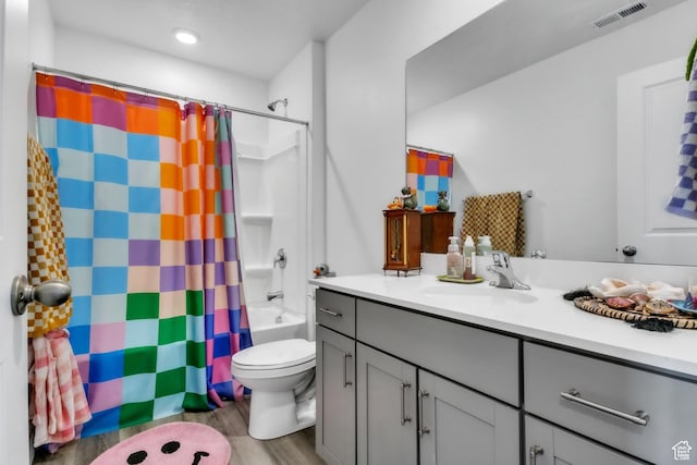 bathroom with toilet, shower / tub combo with curtain, vanity, wood finished floors, and visible vents