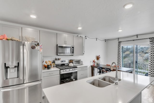 kitchen featuring light countertops, recessed lighting, gray cabinets, stainless steel appliances, and a sink