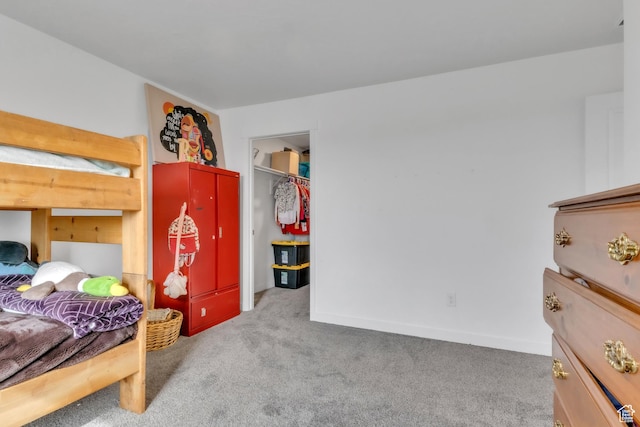 carpeted bedroom with baseboards and a spacious closet