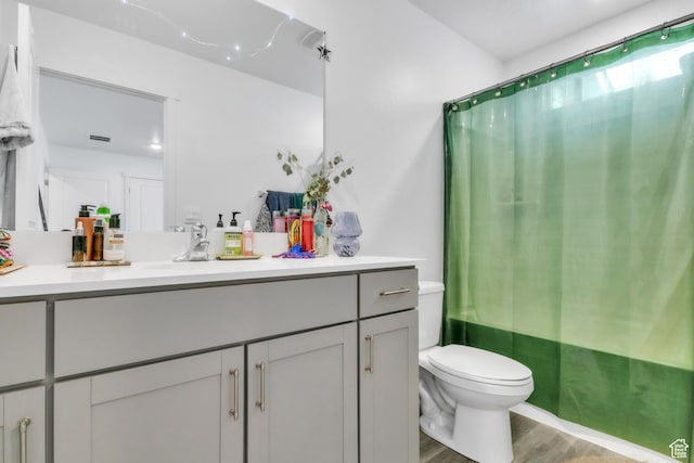 full bath with toilet, vanity, and wood finished floors
