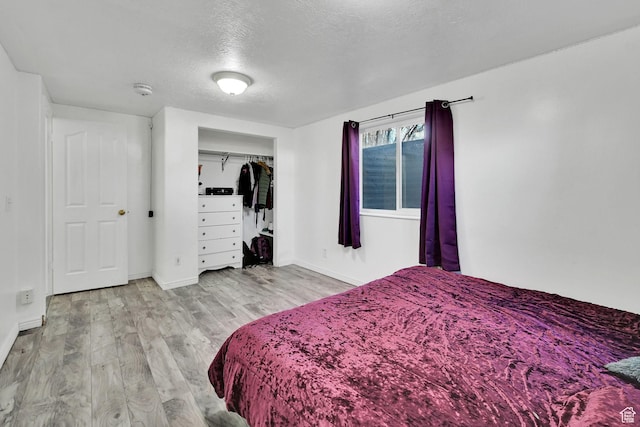 bedroom with a closet, baseboards, wood finished floors, and a textured ceiling
