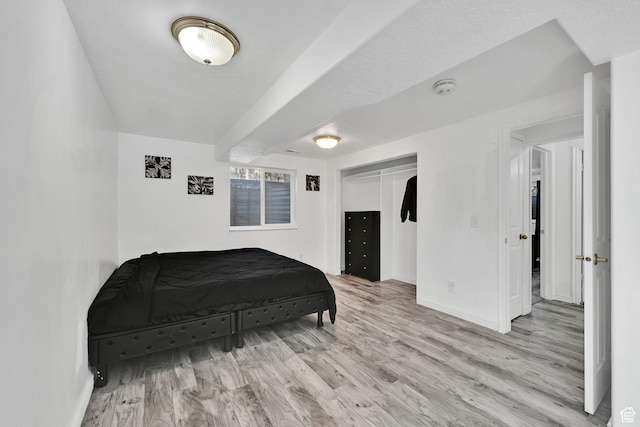 bedroom featuring wood finished floors, baseboards, and a closet