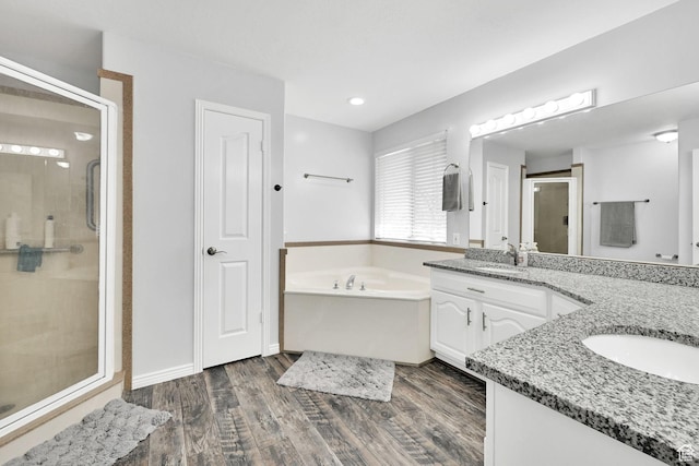 full bathroom featuring a shower stall, vanity, a bath, and wood finished floors