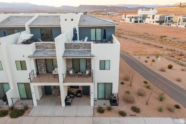 5399 S Cerulean Ln Unit 95, St George, UT 84790 - rear view of property featuring a balcony, stucco siding, stone siding, and concrete driveway