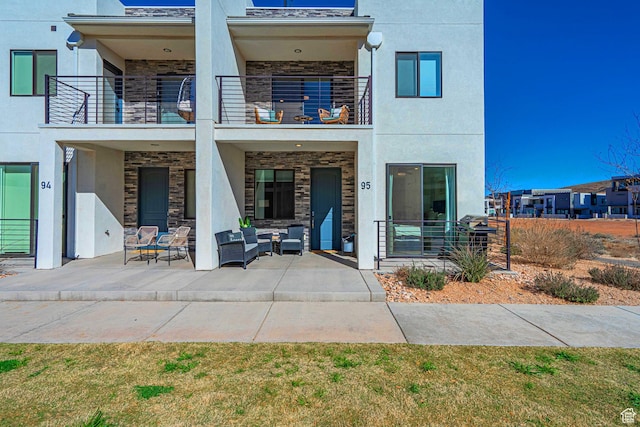 5399 S Cerulean Ln Unit 95, St George, UT 84790 - rear view of property with stone siding, a balcony, stucco siding, and a patio area