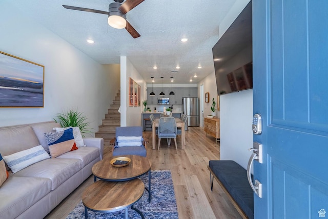 living area with a textured ceiling, recessed lighting, stairway, a ceiling fan, and light wood-type flooring