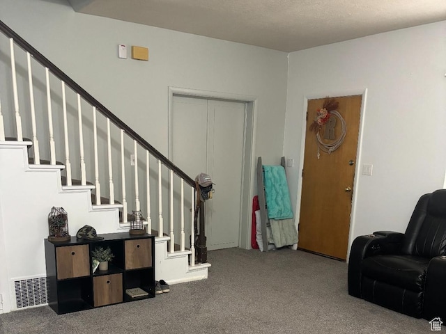 foyer with stairs, visible vents, and carpet