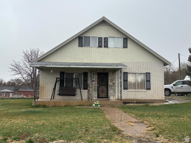 bungalow featuring brick siding, covered porch, and a front yard