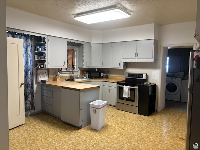 kitchen with a sink, stainless steel appliances, separate washer and dryer, and light floors