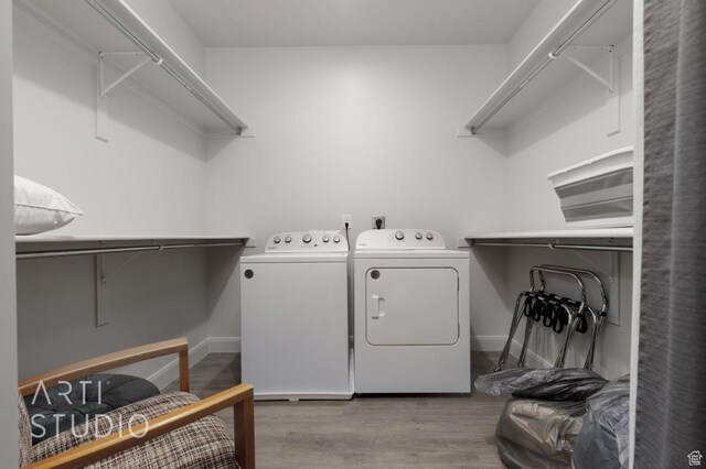 clothes washing area featuring separate washer and dryer, baseboards, laundry area, and wood finished floors