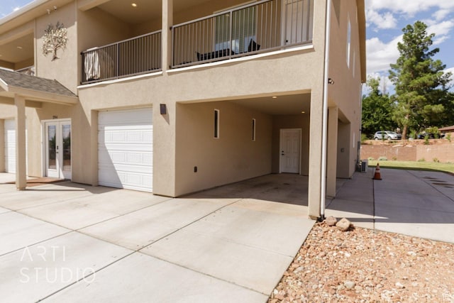 exterior space with french doors, a balcony, driveway, and stucco siding