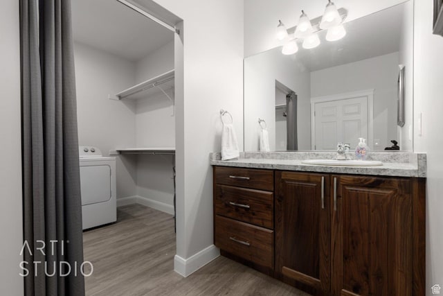 bathroom with a chandelier, baseboards, wood finished floors, vanity, and washer / dryer