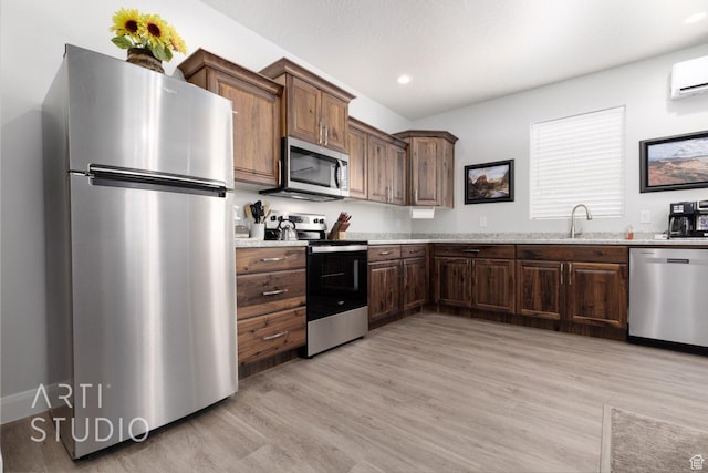 kitchen featuring recessed lighting, appliances with stainless steel finishes, a sink, light wood-type flooring, and a wall unit AC
