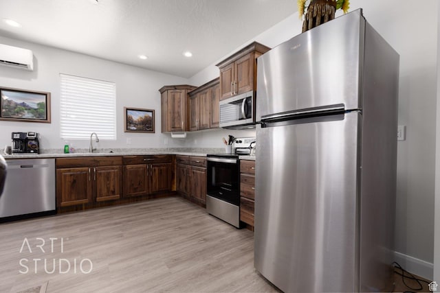 kitchen featuring light wood finished floors, an AC wall unit, recessed lighting, and stainless steel appliances