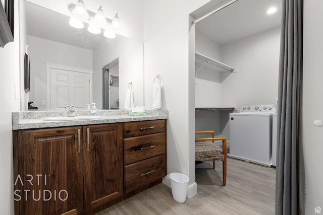 bathroom featuring wood finished floors, vanity, and washer / dryer