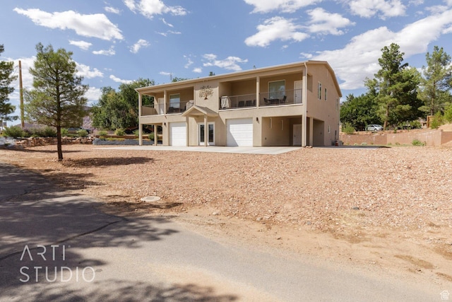 rear view of house featuring a balcony, an attached garage, and stucco siding