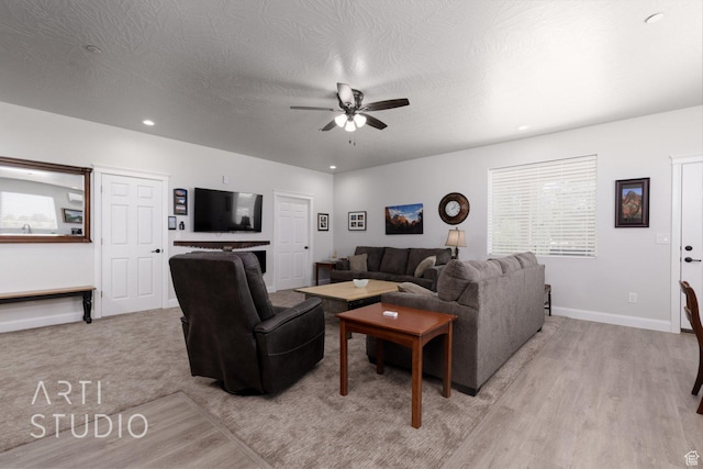living room featuring a textured ceiling, baseboards, light wood-style floors, ceiling fan, and recessed lighting