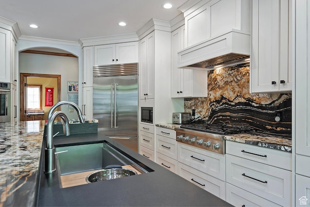 5888 E Pioneer Fork Rd N, Salt Lake City, UT 84108 - kitchen with a sink, appliances with stainless steel finishes, custom exhaust hood, white cabinets, and arched walkways