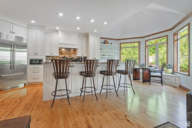 5888 E Pioneer Fork Rd N, Salt Lake City, UT 84108 - kitchen with open shelves, built in appliances, white cabinetry, a breakfast bar, and custom range hood