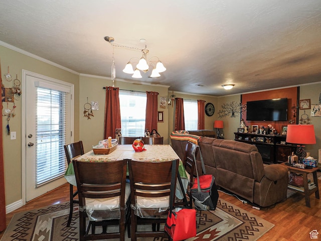 dining area with ornamental molding, wood finished floors, and a chandelier