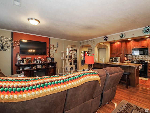 living area with visible vents, crown molding, wood finished floors, and arched walkways