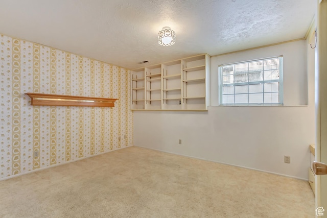 carpeted spare room featuring wallpapered walls, visible vents, and a textured ceiling