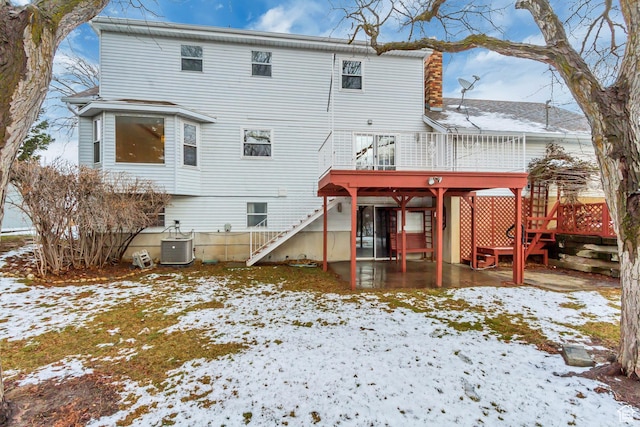 snow covered back of property with stairs, cooling unit, and a wooden deck