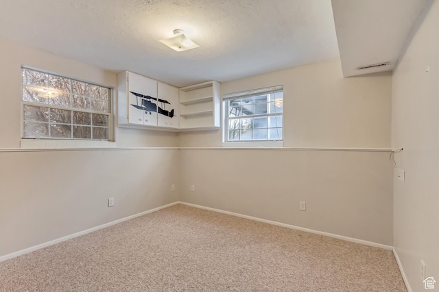 spare room featuring carpet flooring, baseboards, and a textured ceiling