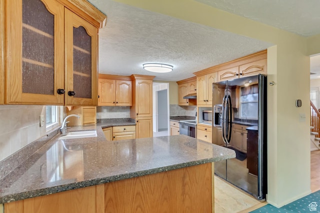 kitchen featuring black fridge with ice dispenser, stainless steel microwave, electric stove, a sink, and a peninsula