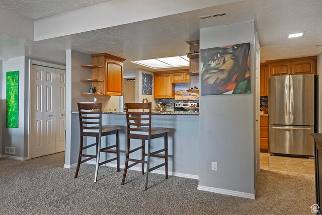 3125 E Kennedy Dr S Unit 605, Salt Lake City, UT 84108 - kitchen with visible vents, light carpet, open shelves, brown cabinetry, and freestanding refrigerator