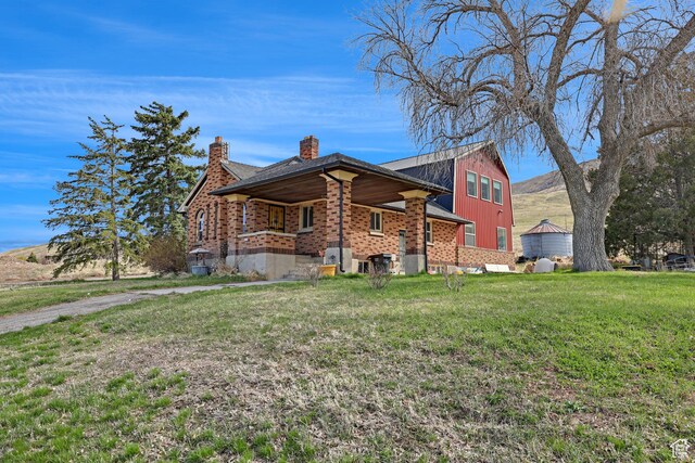 view of front of home with a chimney, board and batten siding, brick siding, and a front yard