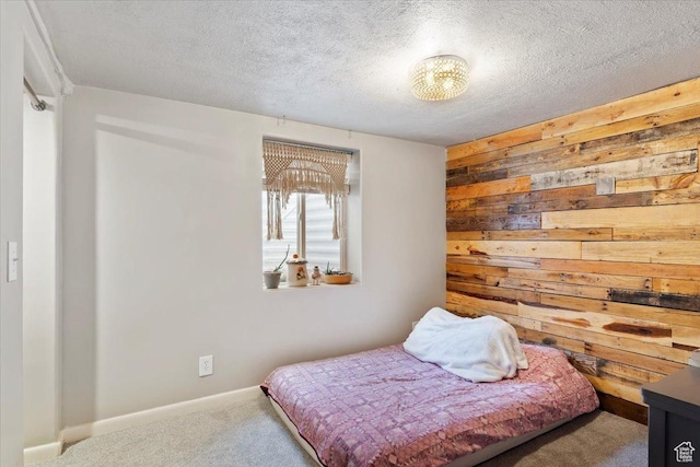 carpeted bedroom featuring baseboards, wooden walls, and a textured ceiling