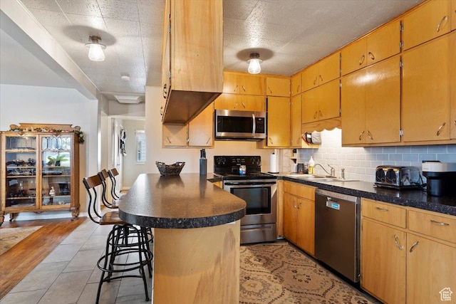 kitchen featuring a sink, dark countertops, appliances with stainless steel finishes, and decorative backsplash