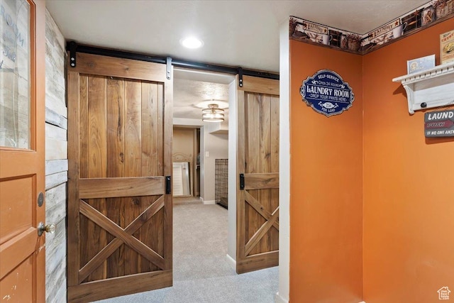 hallway with a barn door and carpet