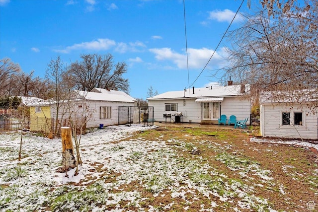 back of property featuring french doors, an outbuilding, and fence