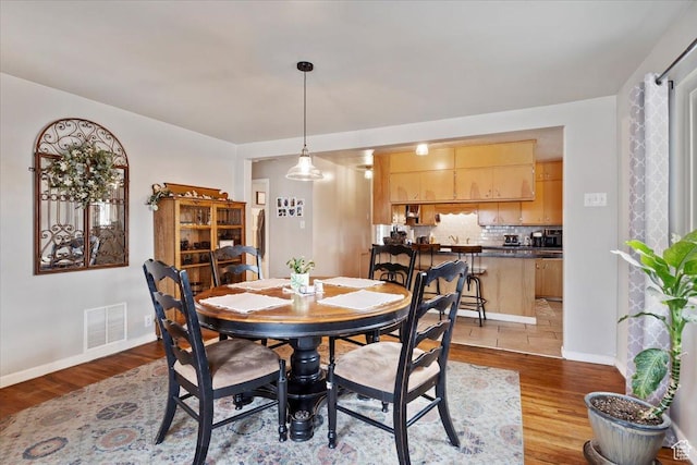 dining area with baseboards, visible vents, and wood finished floors