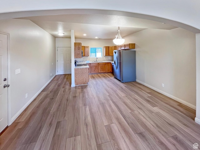 5262 W Cool Water Way, West Jordan, UT 84081 - kitchen with light countertops, light wood-style flooring, baseboards, brown cabinets, and stainless steel refrigerator with ice dispenser