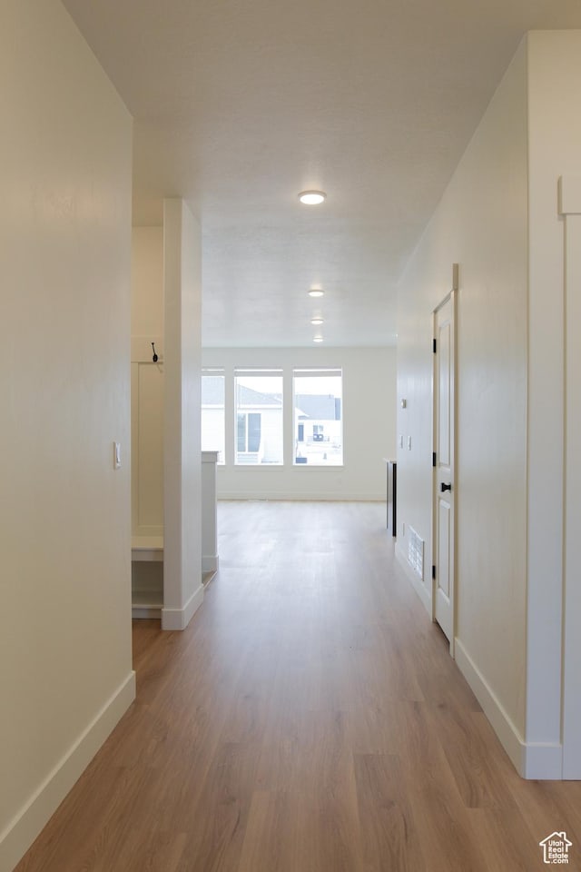 corridor with baseboards and wood finished floors