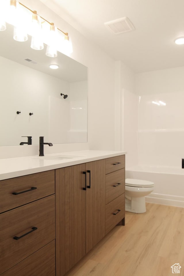 full bathroom featuring toilet, wood finished floors, vanity, visible vents, and  shower combination