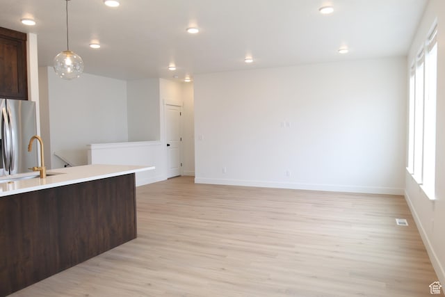 kitchen featuring plenty of natural light, a sink, stainless steel refrigerator with ice dispenser, and dark brown cabinetry