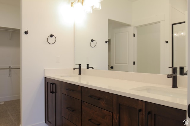 bathroom with double vanity, a chandelier, a walk in closet, and a sink